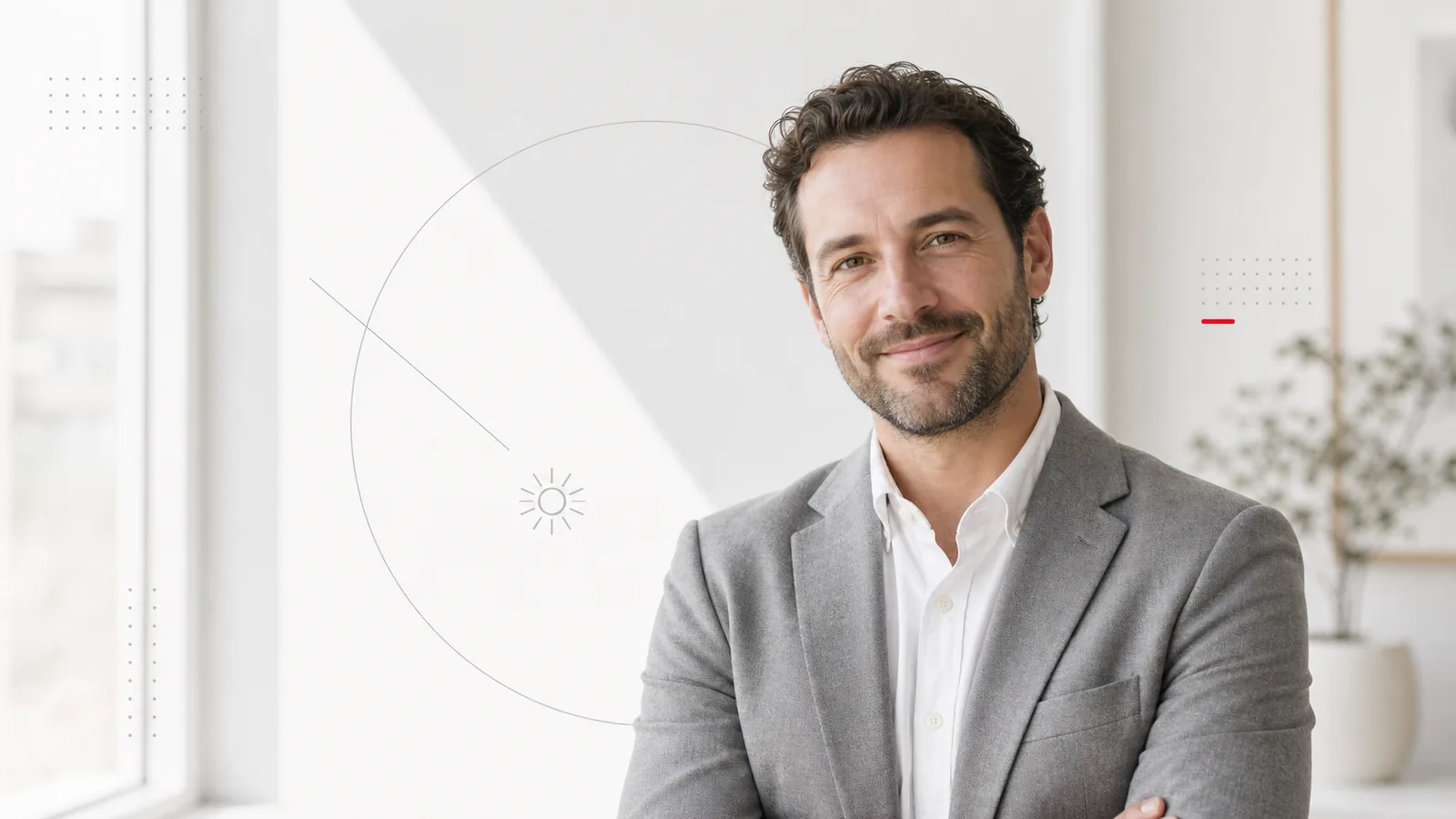 Business-Portrait eines lächelnden Mannes mit kurzen dunklen Haaren in hellem Sakko vor heller Fensterfront, aufgenommen mit natürlichem Tageslicht ohne Studio-Setup