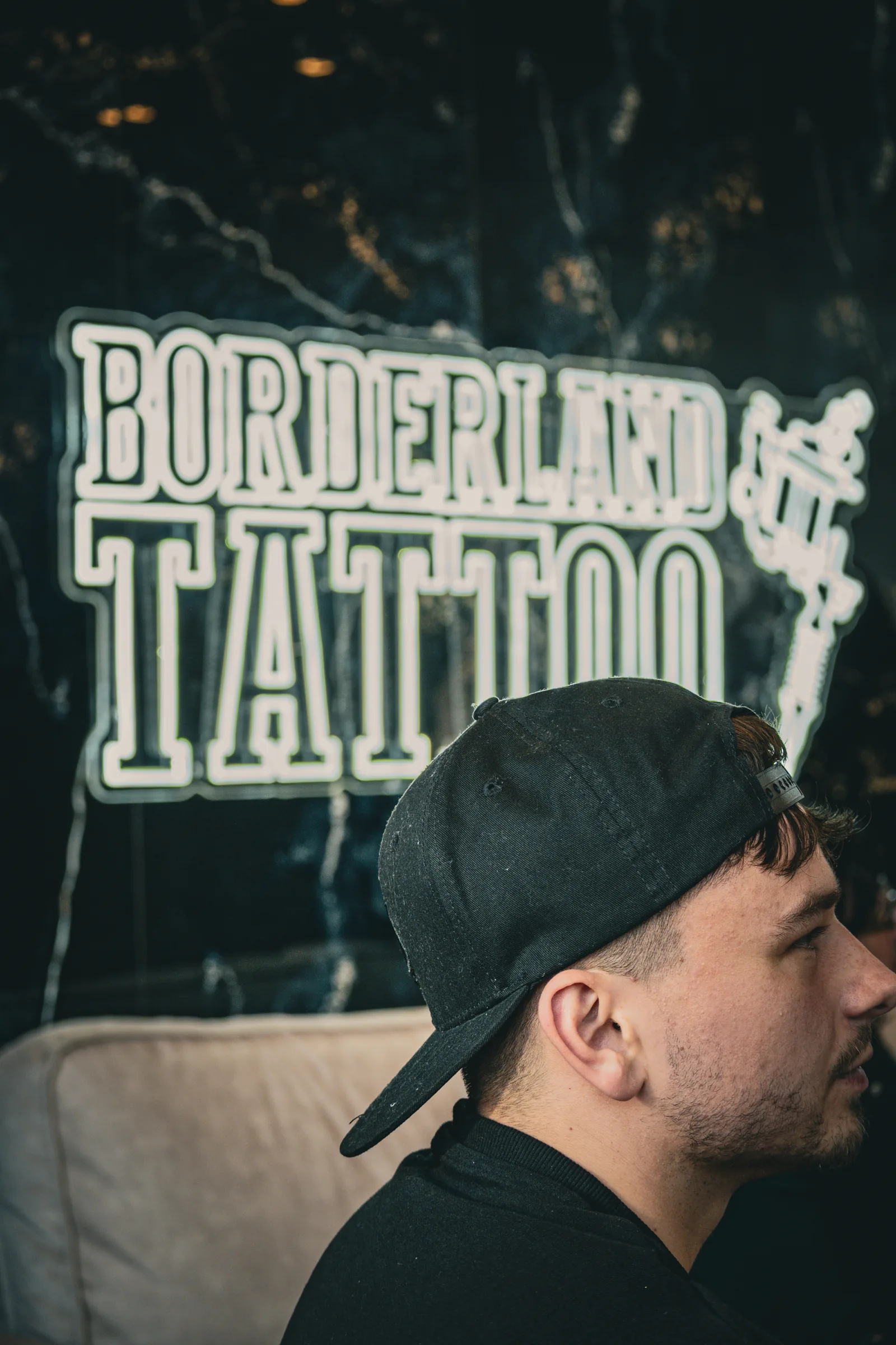 Gast mit Cap vor dem Neon-Schriftzug — Neueröffnung Borderland Tattoo Aachen, Event-Reportage, Foto eoglou media design Aachen