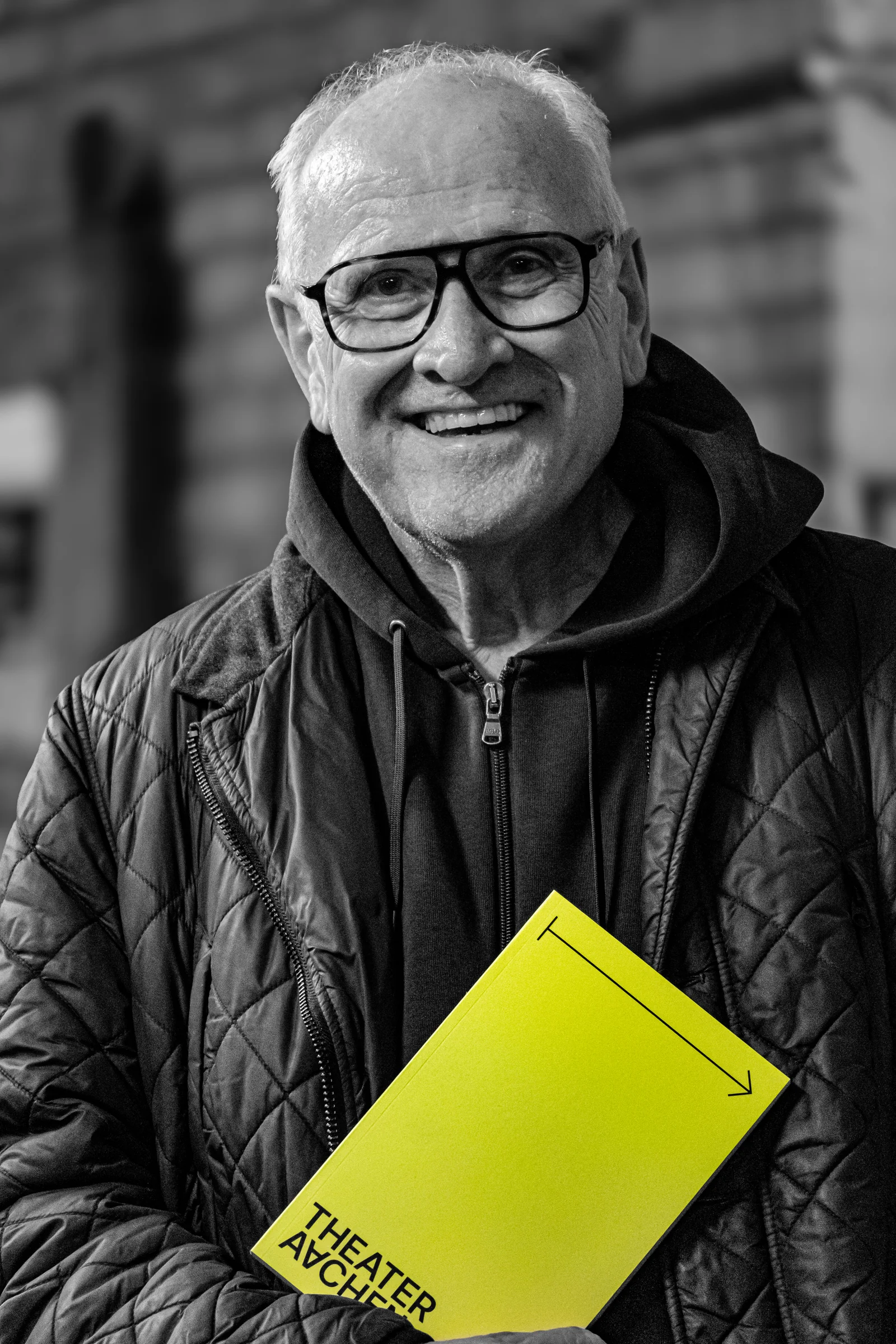 Portrait Aachen — Sjef mit Theaterprogramm vor schwarz-weißem Hintergrund, Editorial-Fotografie mit Nikon Z50 II, Februar 2026, von Emrach aus Aachen